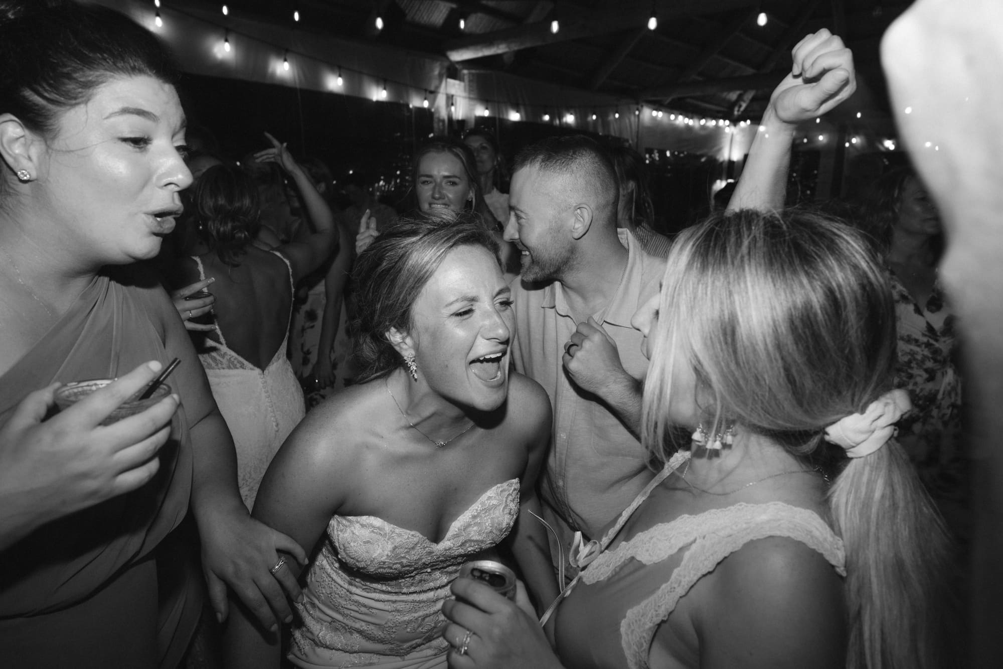 Bride laughing with bridesmaids in a candid black-and-white moment at a Modern Era Weddings reception