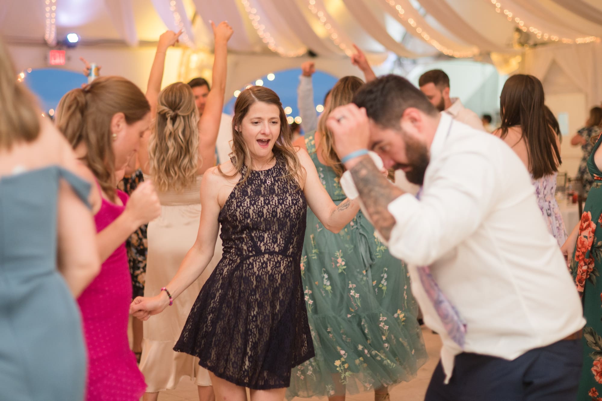 Tented outdoor wedding reception dance floor lit with string lights at a Signature Wedding Weekend