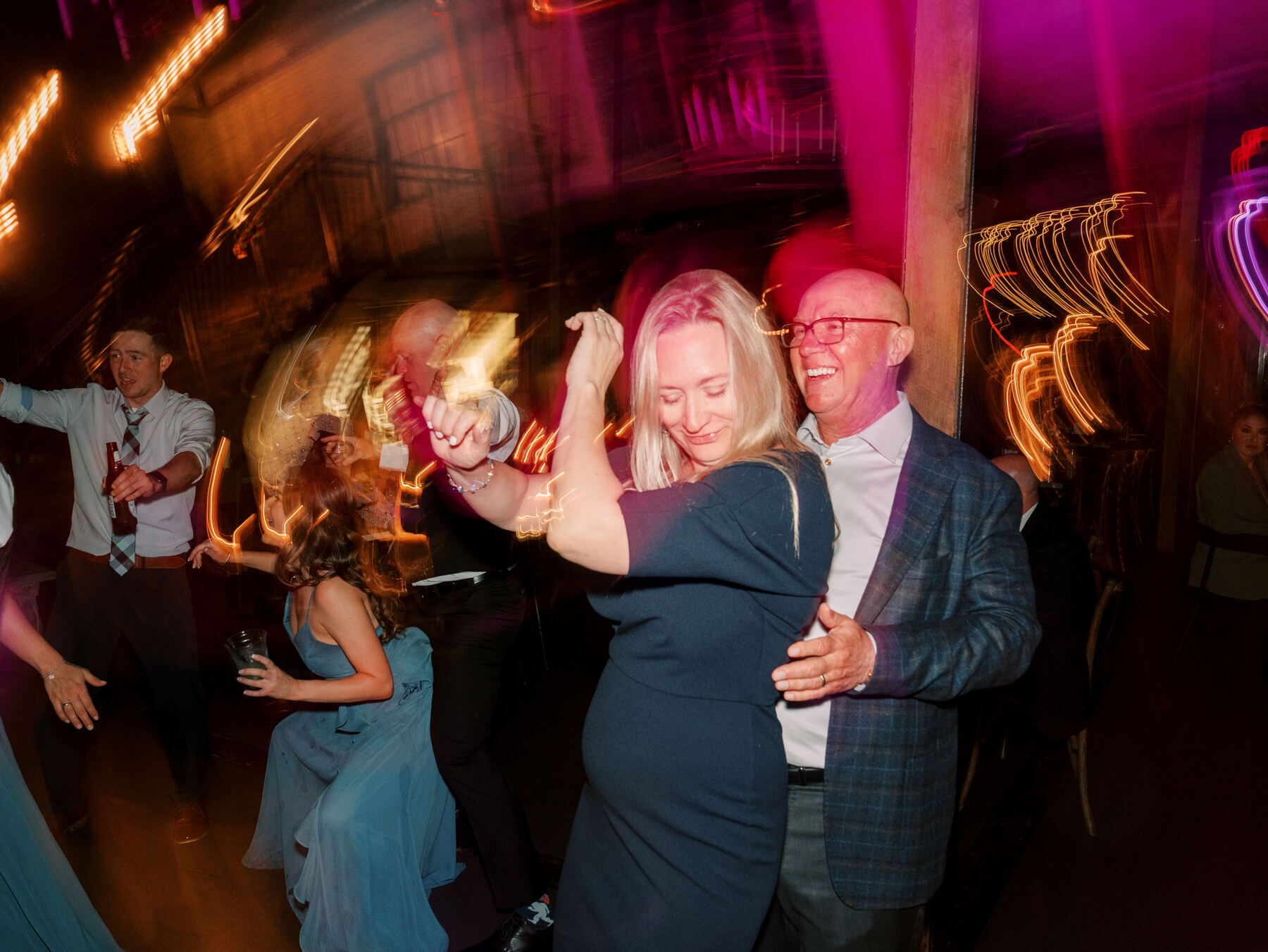 Couple dancing under neon light trails at a Modern Era Weddings reception
